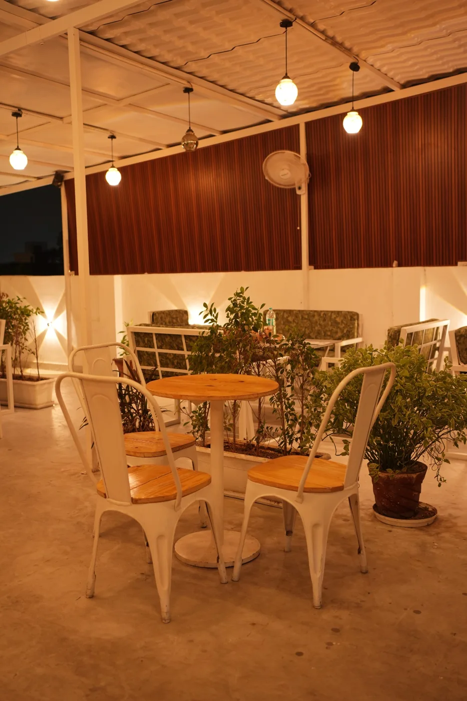 Cafe tables and chairs under a covered seating area with warm lighting. Nasha Chai Sutra, SFS Mansarovar Jaipur.